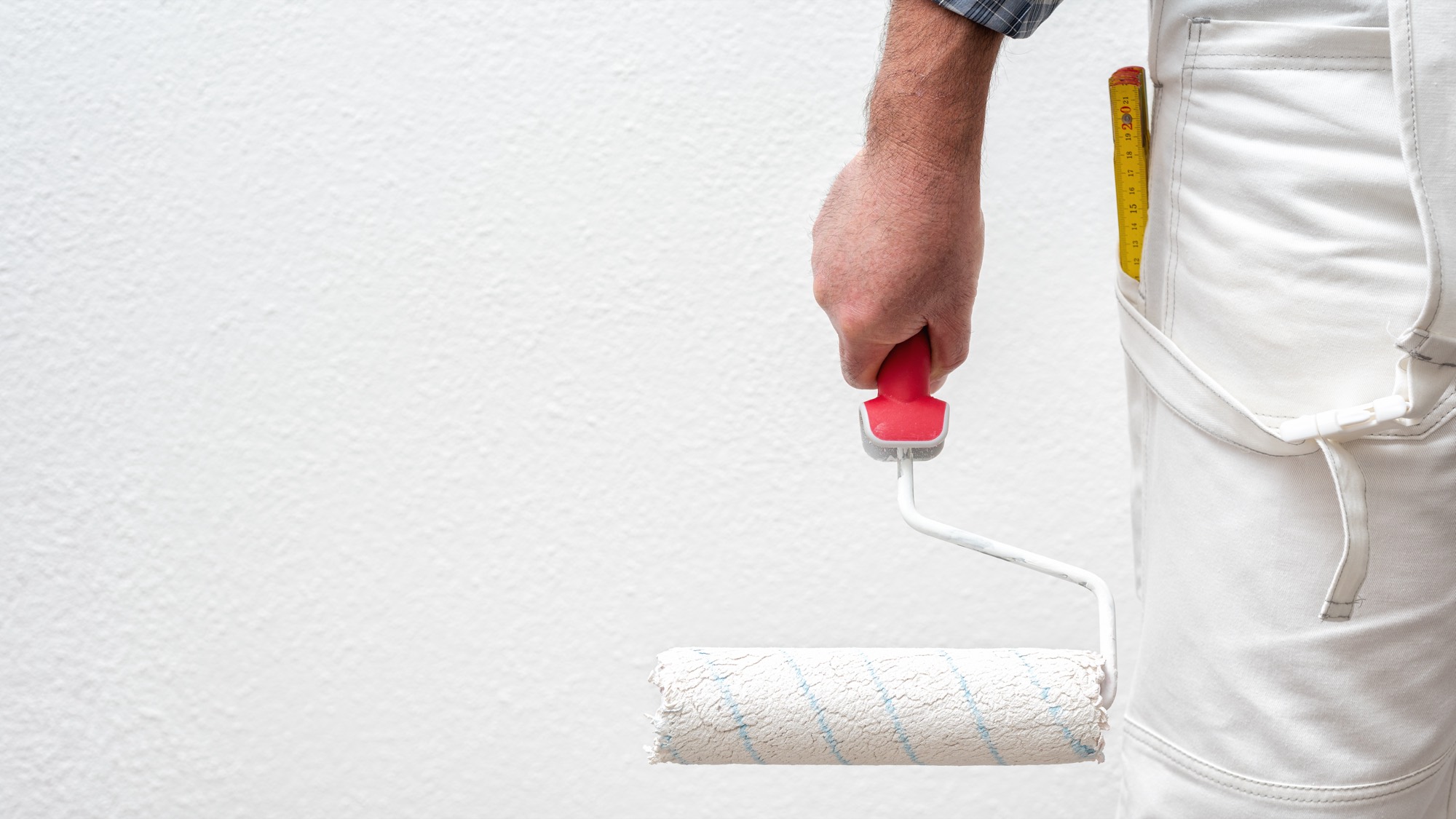 Rullo da imbianchino carico di pittura davanti a una parete bianca